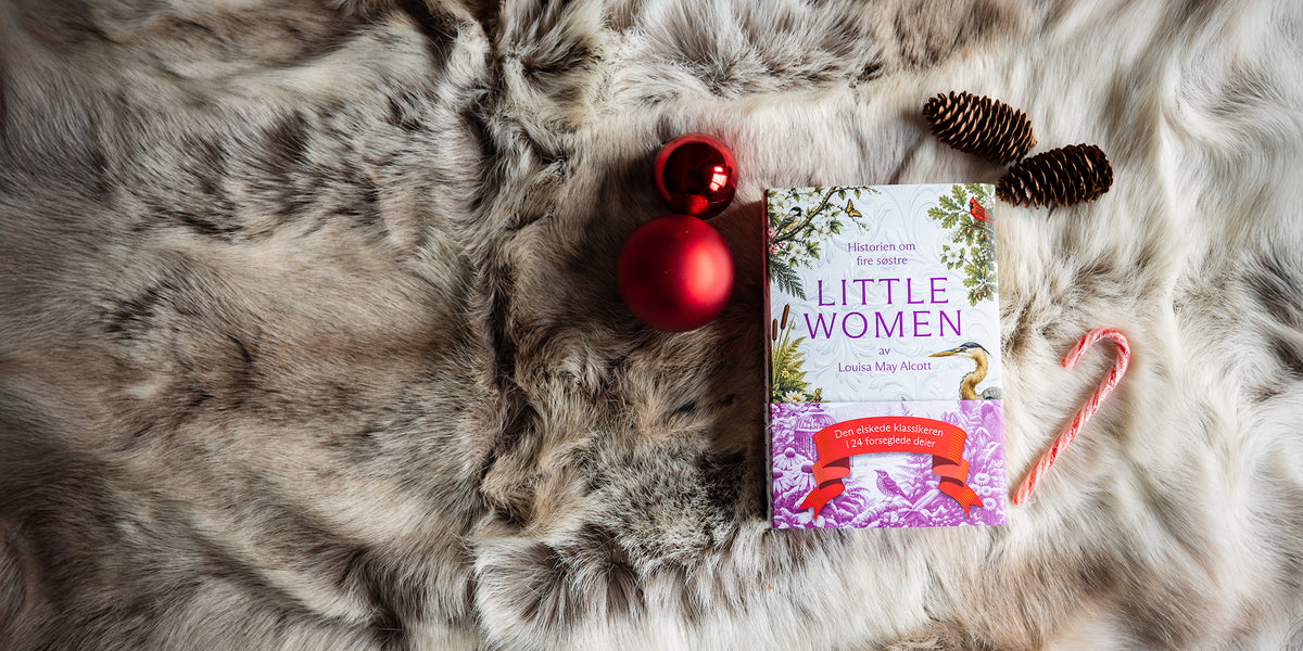 Little Women av Louisa May Alcott på et pelsteppe, med en rød julekule, kongler og en polkagris