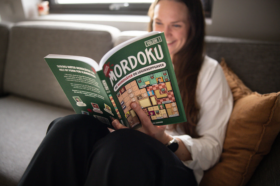 Kvinne i sofaen leser Mordoku, grønt omslag med gulvplan